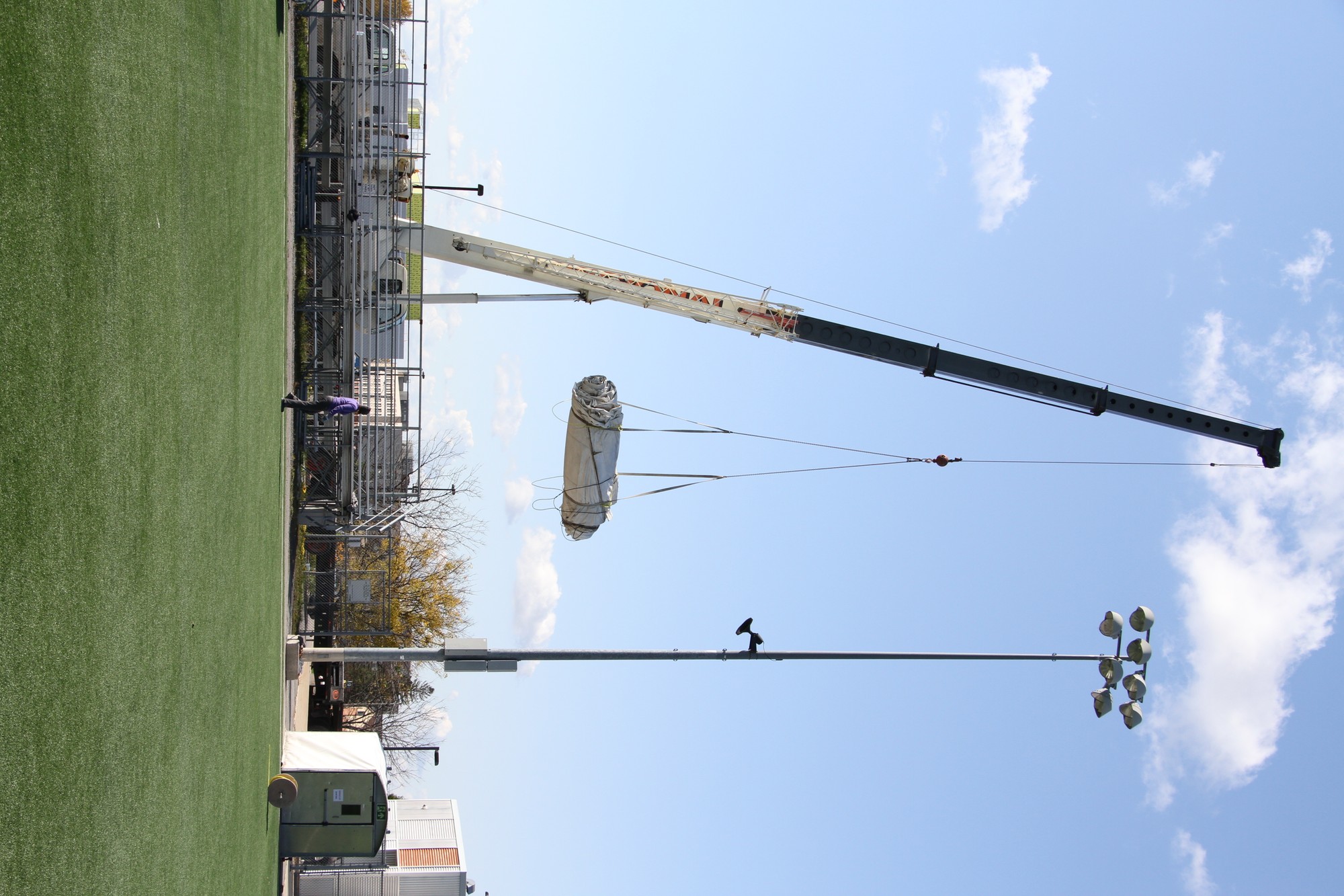 Martha Peak, senior manager of Athletics and Recreation, walks by as the crane lifts the largest tarp off the field.